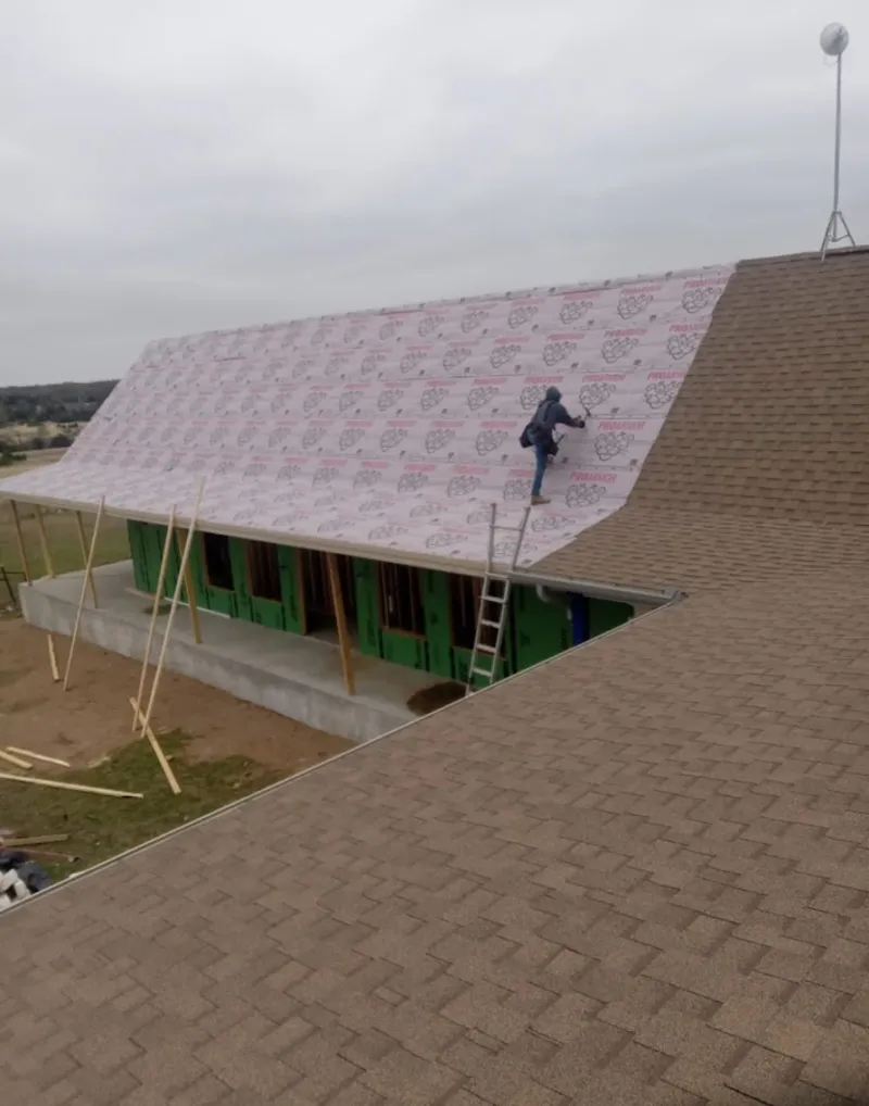 Worker preparing underlayment for a metal roof installation in Grafton